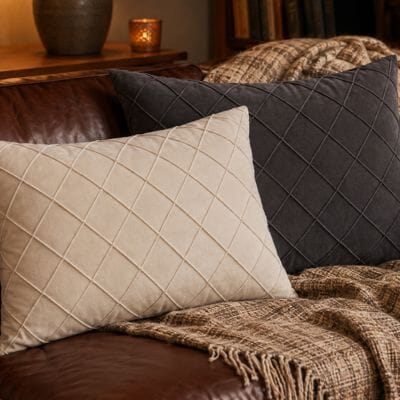 Housses coussin blanc crème et gris anthracite matelassées sur canapé en cuir