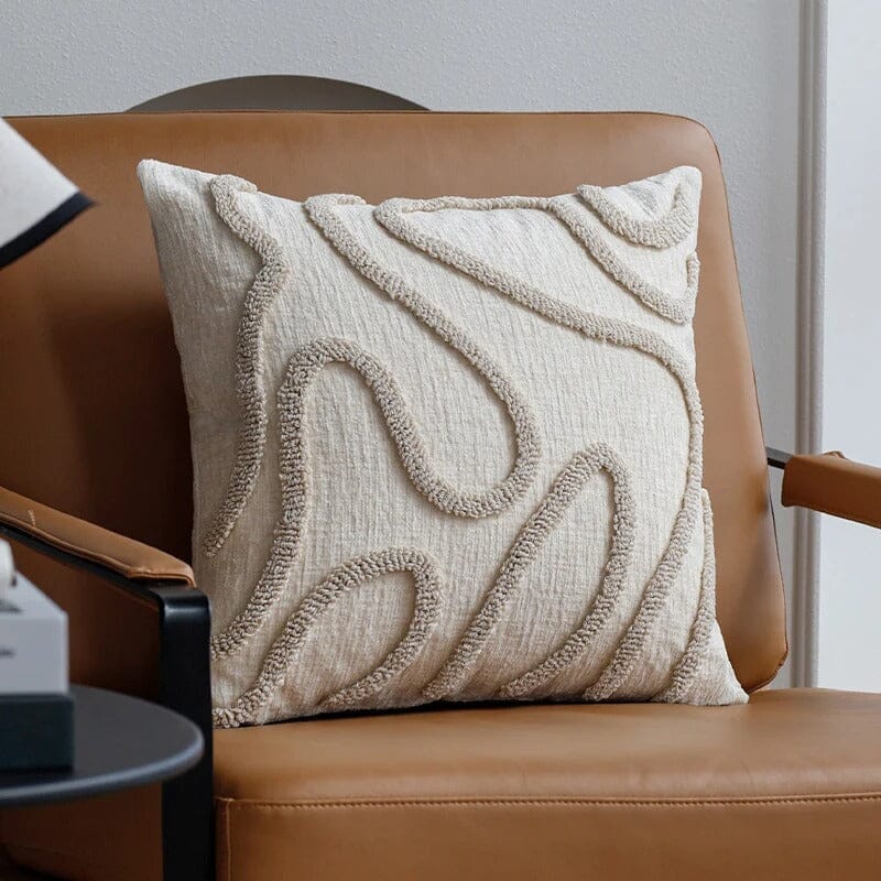 Housse de coussin Chenille Boho beige en tissu texturé sur fauteuil en cuir camel pour une décoration de salon chaleureuse