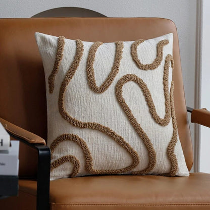 Housse de coussin Chenille Boho café en tissu texturé sur fauteuil en cuir camel pour une décoration de salon chaleureuse