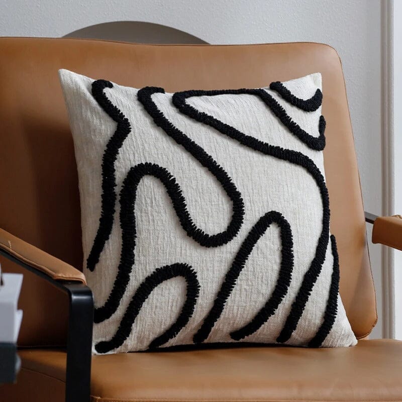 Housse de coussin Chenille Boho noir en tissu texturé sur fauteuil en cuir camel pour une décoration de salon chaleureuse
