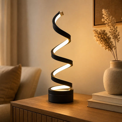 Lampe salon Lueur Spirale noire diffusant une lumière chaleureuse sur une console en bois