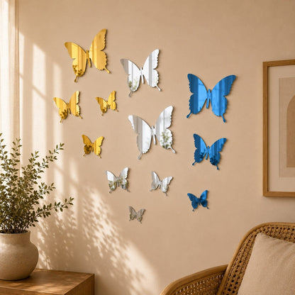 Stickers muraux papillons miroir en trois variantes, bleu, doré et argenté, présentés en gros plan sur un mur beige dans un intérieur chaleureux.