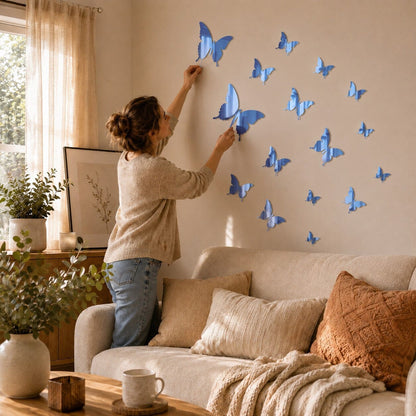 Maman installant des stickers muraux papillons bleu miroir sur le mur d’un salon lumineux et chaleureux.